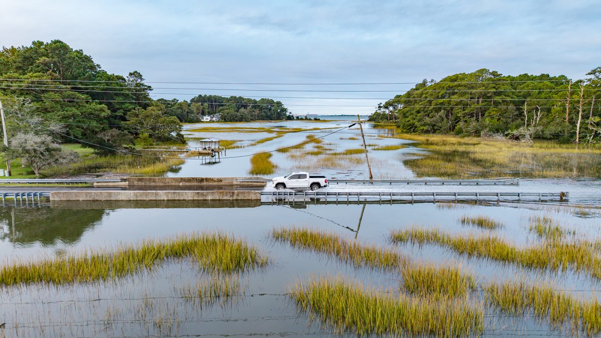 A motorist slows down to cut through the high tide waters of Russell Creek Friday morning near Beaufort. Photo: Dylan Ray