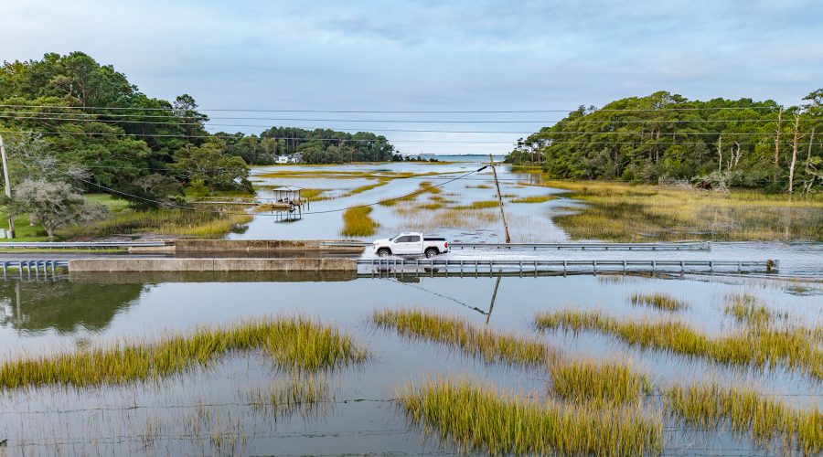 A motorist slows down to cut through the high tide waters of Russell Creek Friday morning near Beaufort. Photo: Dylan Ray