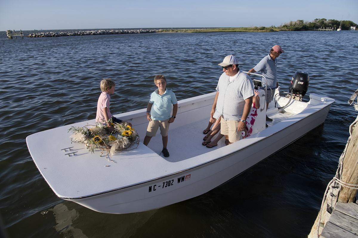 By tradition, children deliver the wreath honoring those of the fishing community who have “crossed the bar” for the last time. George Scott in blue and Russell Edwards in red prepare to leave the dock with Captain of the Miss Hatteras KP Edwards at the helm. Photo: Kip Tabb