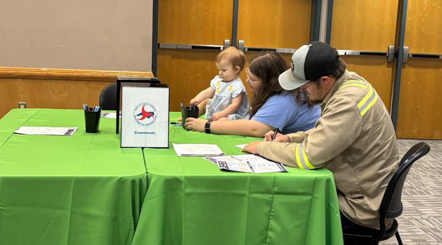 Beaufort County resident John Richards fills out a comment form at Tuesday's listening session hosted by the N.C. Ferry Division in Washington while his wife, Rene, entertains the couple's 1-year-old daughter, Elsie Mae. Photo: Trista Talton