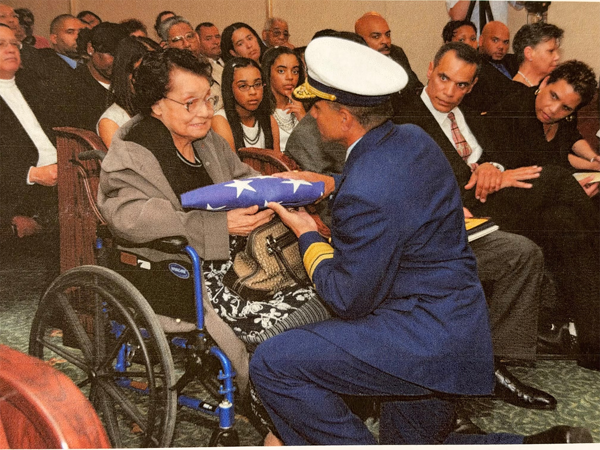 I, Joan Collins, am shown seated at right on the front row looking toward my mother during my father’s memorial service in March 2010 as she is handed a flag by U.S. Coast Guard Rear Adm. Mason Brown, who, two years later, became the first African American to achieve the Coast Guard rank of vice admiral. Photo: U.S. Coast Guard