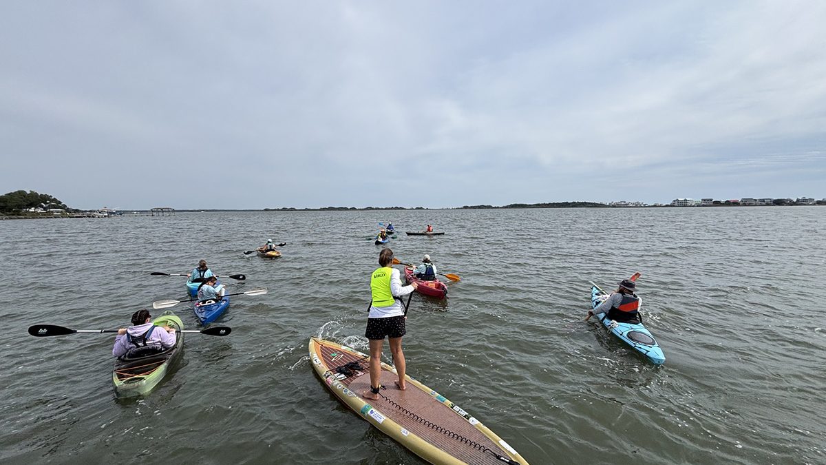 A flotilla of paddlers, the first group of volunteers with a new research and community science initiative launched by Coastal Carolina Riverwatch and the University of North Carolina Wilmington with funding by North Carolina Sea Grant, embarks on an initial field survey of submerged aquatic vegetation. Photo: Trista Talton